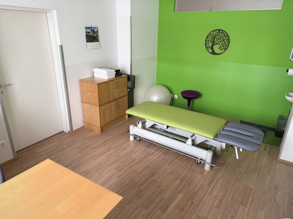 Behandlungsraum mit Therapieliege und grüner Wand im Therapie Zentrum Korneuburg